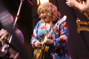 Lindsey Walker plays the guitar on stage with her band.