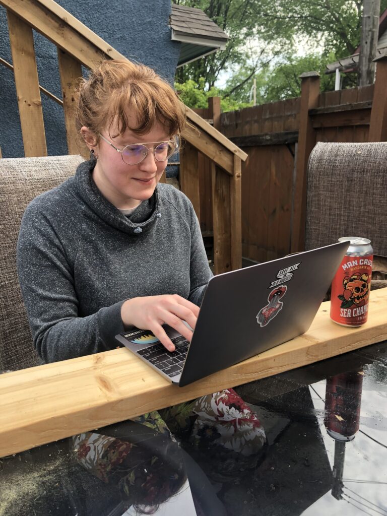 AJ writing at their desk with a can of Sea Change Man Crush