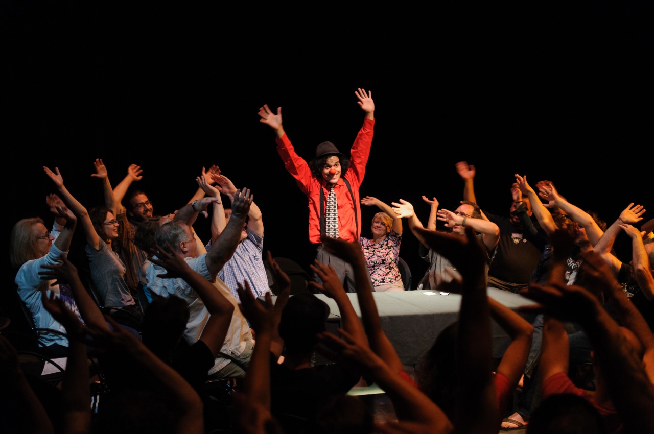 Ewerton Martin in clown has his hands in the air. He is surrounded be people who also have their hands in the air.