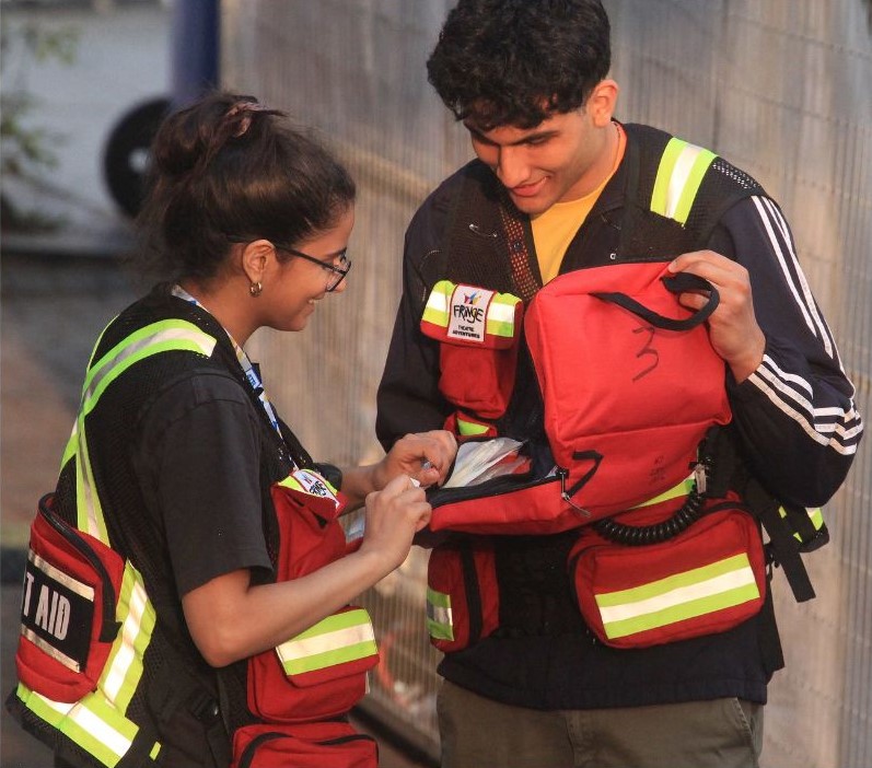 2 First Aid team members in high visible vests open a first aid pack
