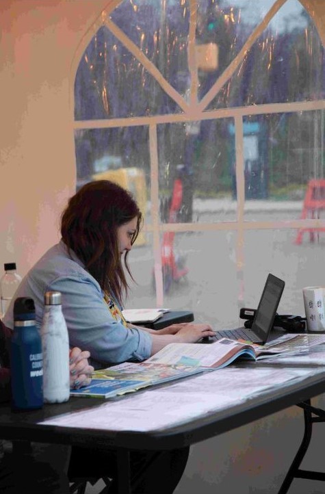 Volunteer typing at a computer in a tent.