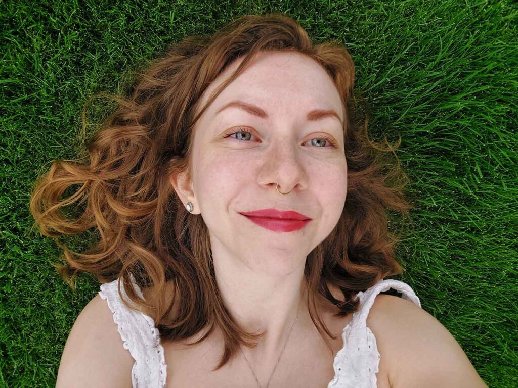A photo of Jenica laying on green grass.