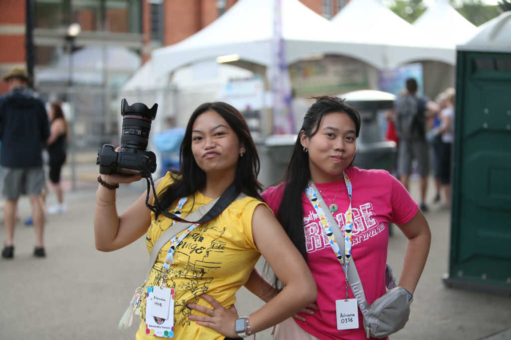 Two Volunteers posing while one holds a DSLR camera