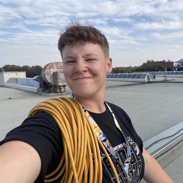 Liv on a rooftop with yellow cable on their arm.