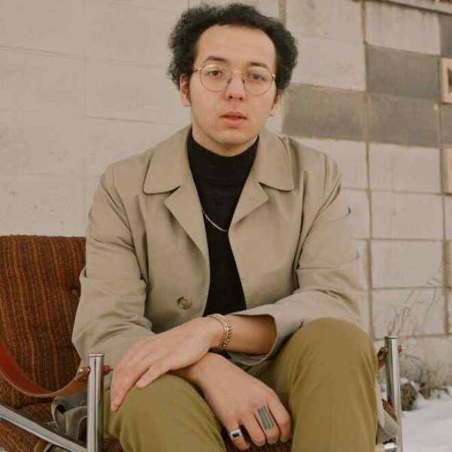 Artist is sitting down in a suit.