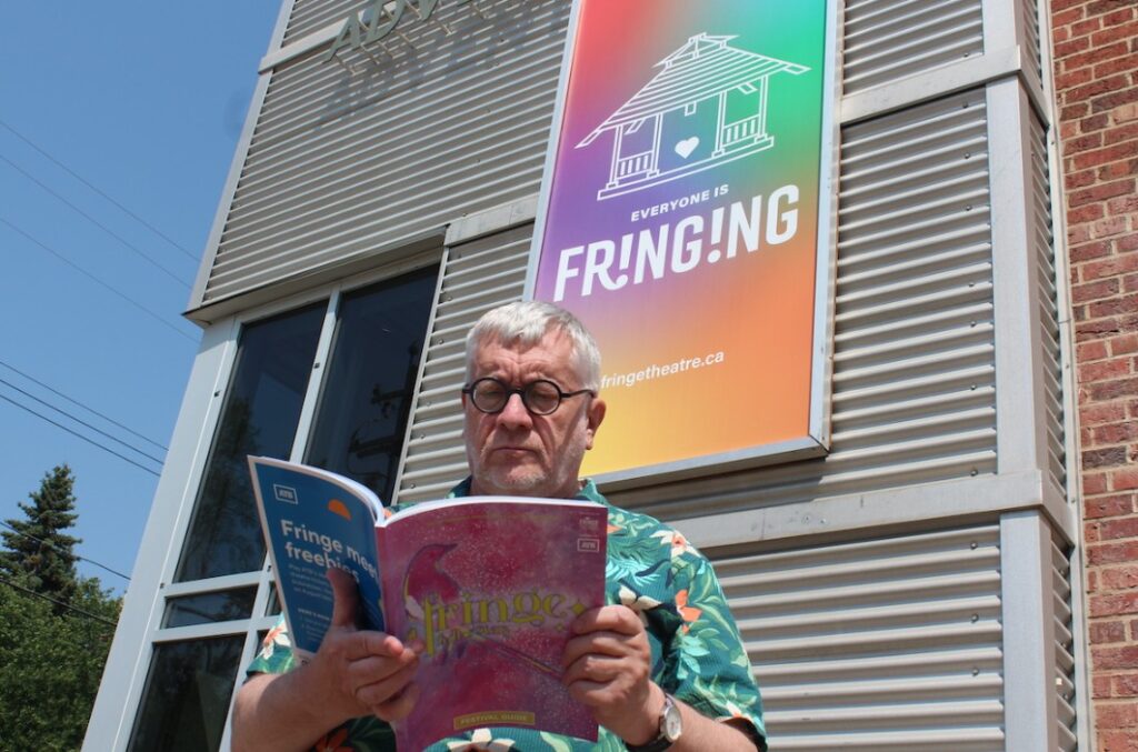 Gerald Osborne reading a Festival Guide outside of the Arts Barn.
