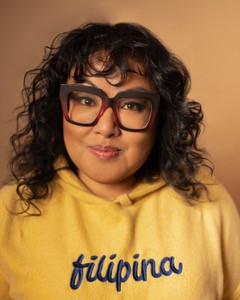 A headshot of Gina Puntil wearing large glasses and a yellow sweater.