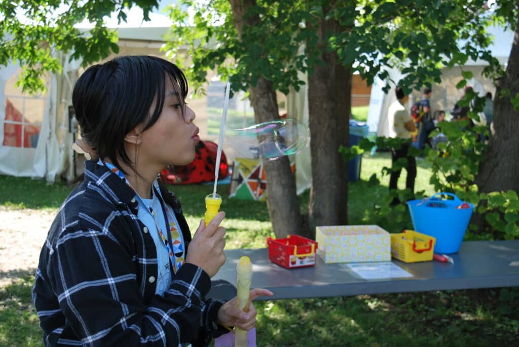 KidsFringe Volunteer blowing bubbles.