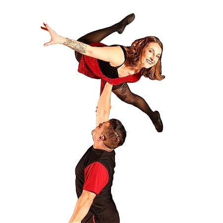 Two performers in black and red. A performer balances on the others hand.