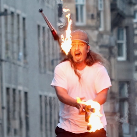 A performer juggles flaming batons.